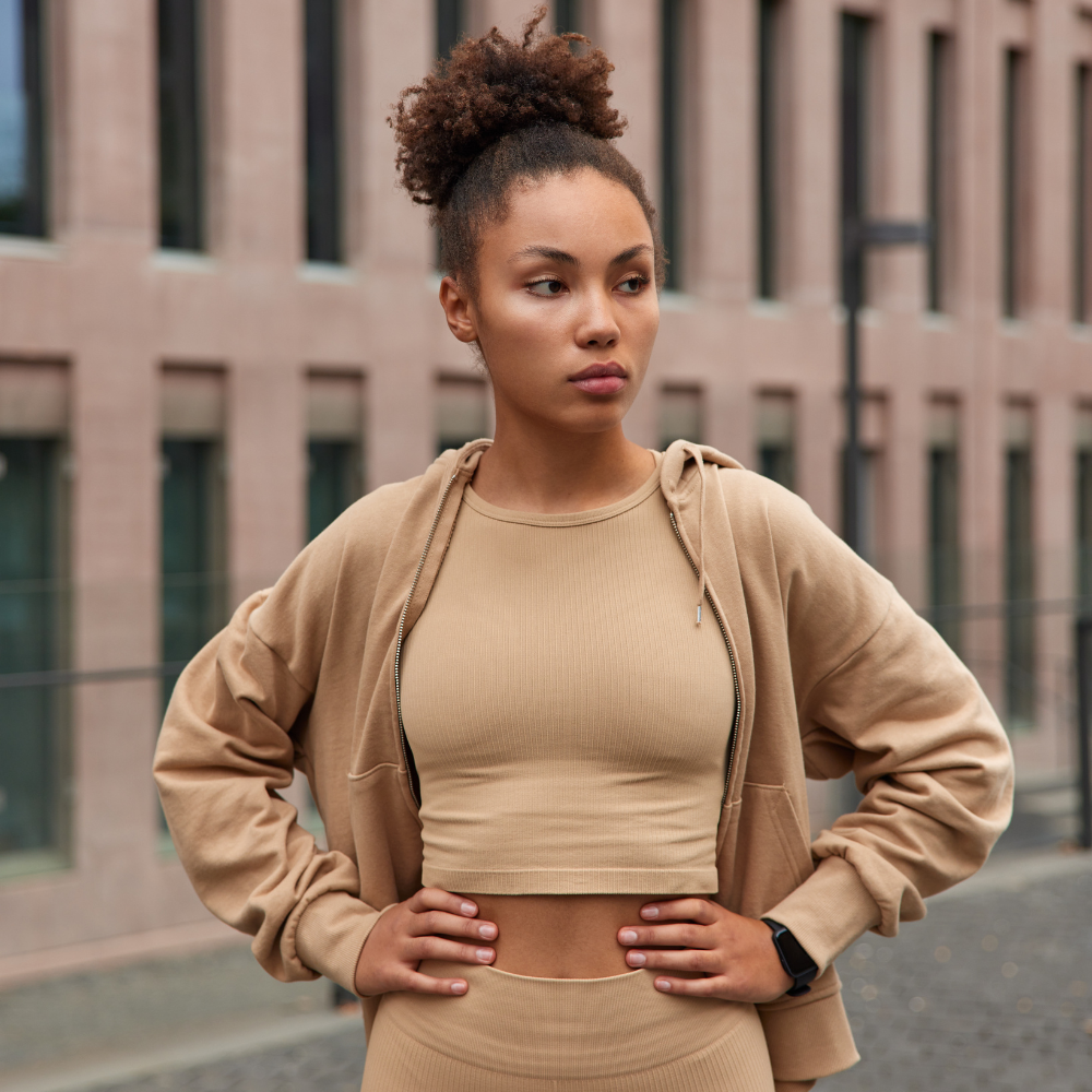 Woman wearing a beige tracksuit standing in front of a building

